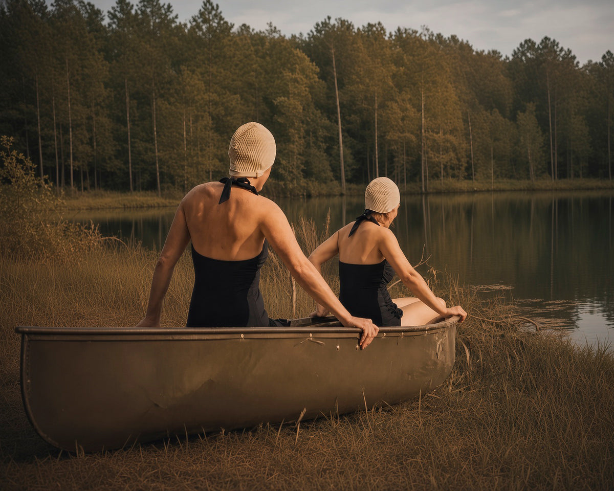 Two women pausing together in a canoe at the edge of a summer lake