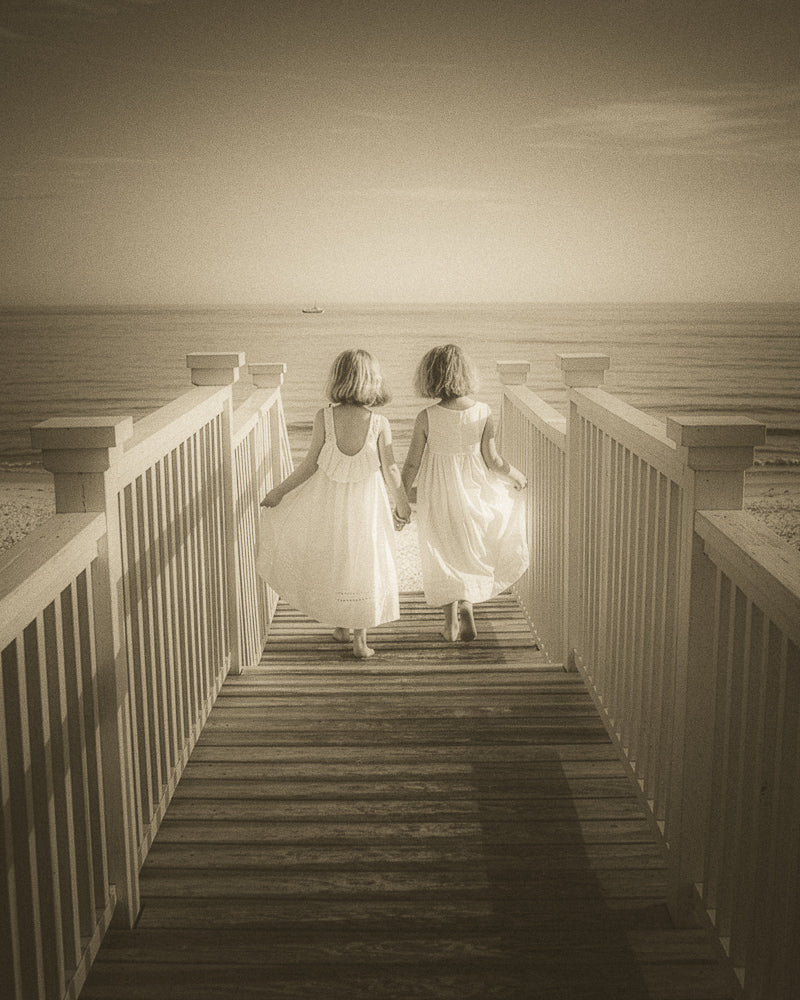 Two friends walking hand-in-hand toward the sea
