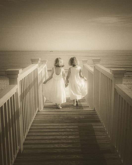 Two friends walking hand-in-hand toward the sea