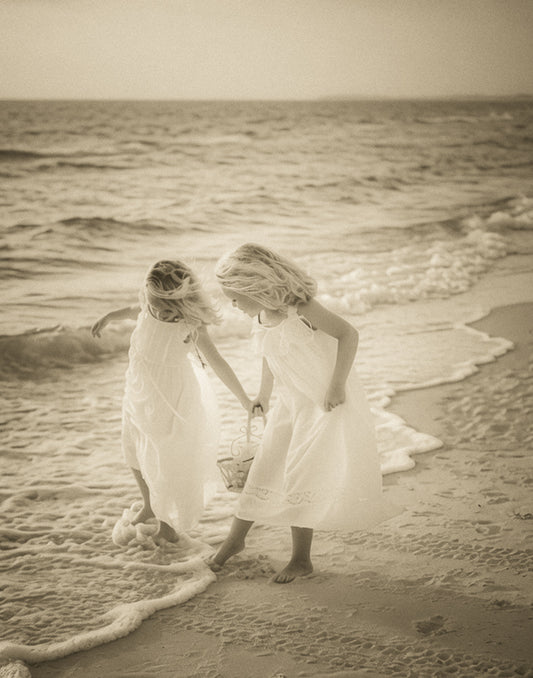 Two friends combing the shoreline collecting shells