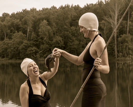 A woman proudly holding up the day's catch while her friend laughs beside her